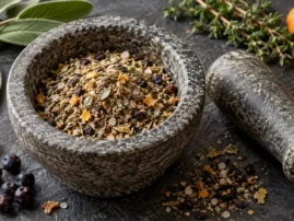 Juniper sage quail rub in a stone mortar with juniper berries, sage and thyme