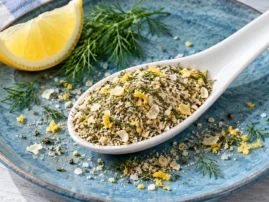 Lemon dill fish rub on a white spoon with fresh dill and a lemon wedge