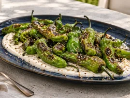 Blistered shishito peppers with sesame-lime yogurt and toasted sesame seeds.