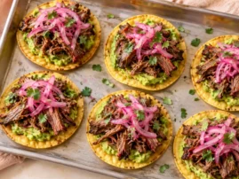 Mini tostadas topped with smoked shredded chuck roast, avocado, pickled red onion, and cilantro.