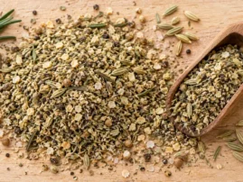 Rosemary fennel lamb rub with whole fennel seeds and a rosemary sprig, in a wooden scoop