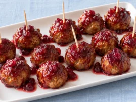 Cranberry-glazed turkey meatballs arranged on a platter with appetizer toothpicks.